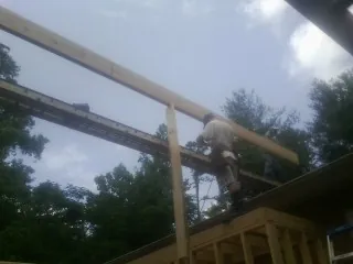 Carpenter setting a ridge beam over a new addition frame — Ice Dam Removal by Roofing Brothers in Cat Spring