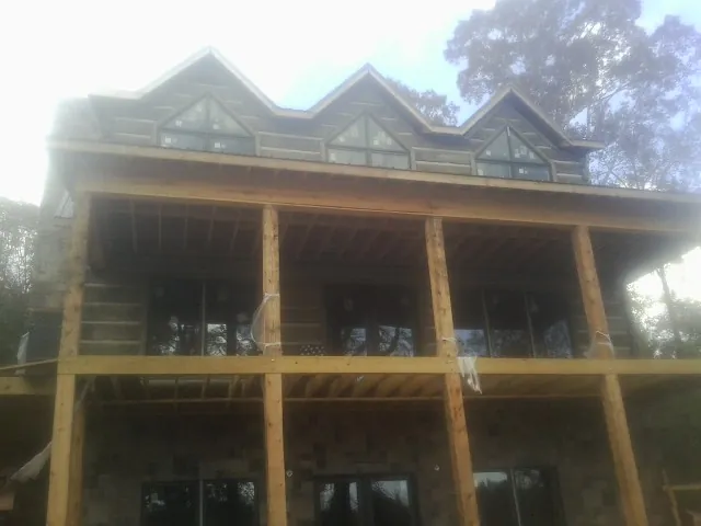 Dormers and porch framing on a large log home under construction — Roof Coating work by our crew in Cat Spring
