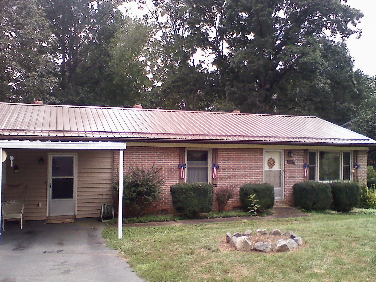 Bronze metal roof and carport on a brick ranch home — Roof Repair work by our crew in Cat Spring